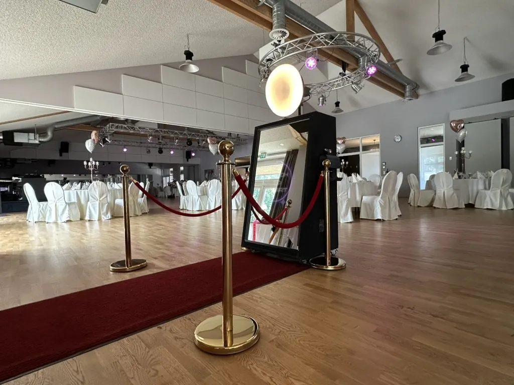 Roter Teppich mit goldenen Absperrpfosten vor der Fotobox Spiegel Pro in einer Halle